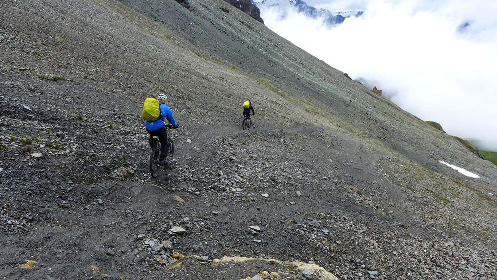 Zwei Mountainbiker fahren auf weichem Untergrund vom Pas de Lona ab.