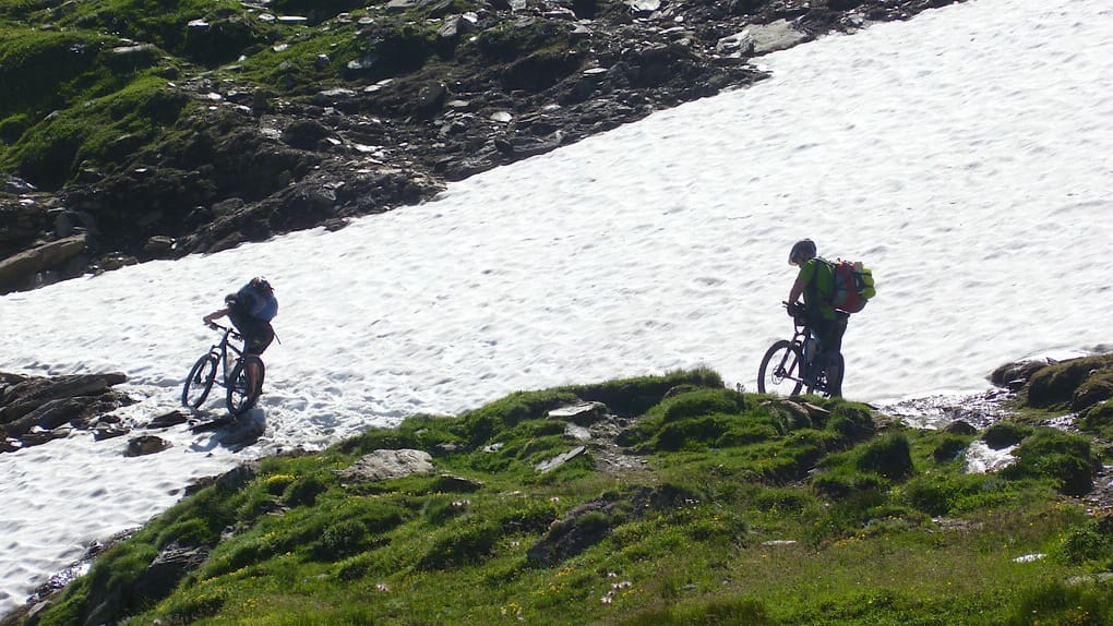 Zwei Mountainbiker an einem Altschneefeld