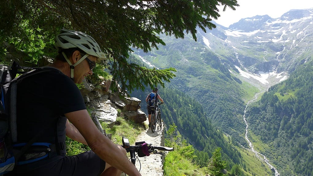 Zwei Biker auf einem schmalen Pfad hoch über einem Tal im Wallis