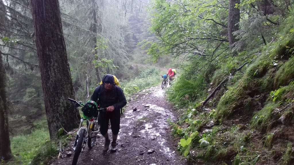 zwei Biker schieben im Regen ihre Räder hoch zum Passo Palombino