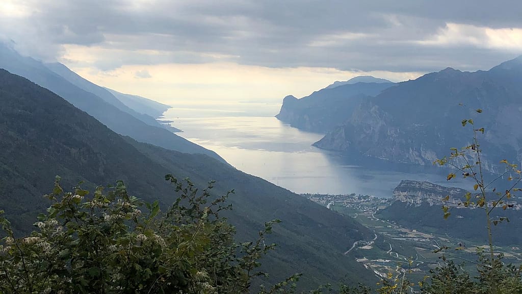 Von hoch oben geht der Blick Richtung Süden. Man sieht den Gardasee zwischen seinen Bergen liegen. Im Vordergrund Torbole und der Brione.