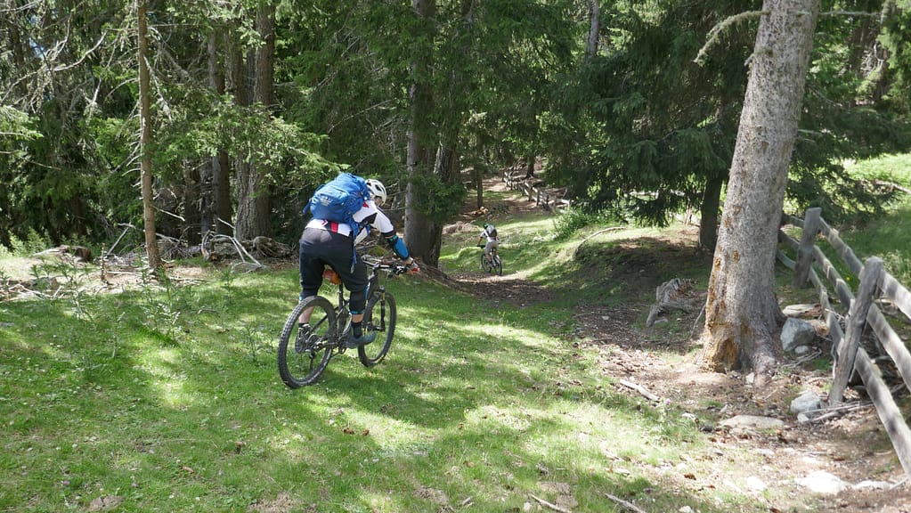 Zwei Biker fahren einen Trail steil bergab